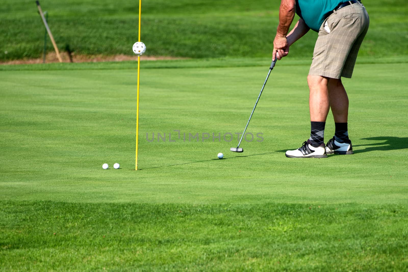 Golfer, golf player, on the green, mature male putting with several balls, not recognizable, copyspace
