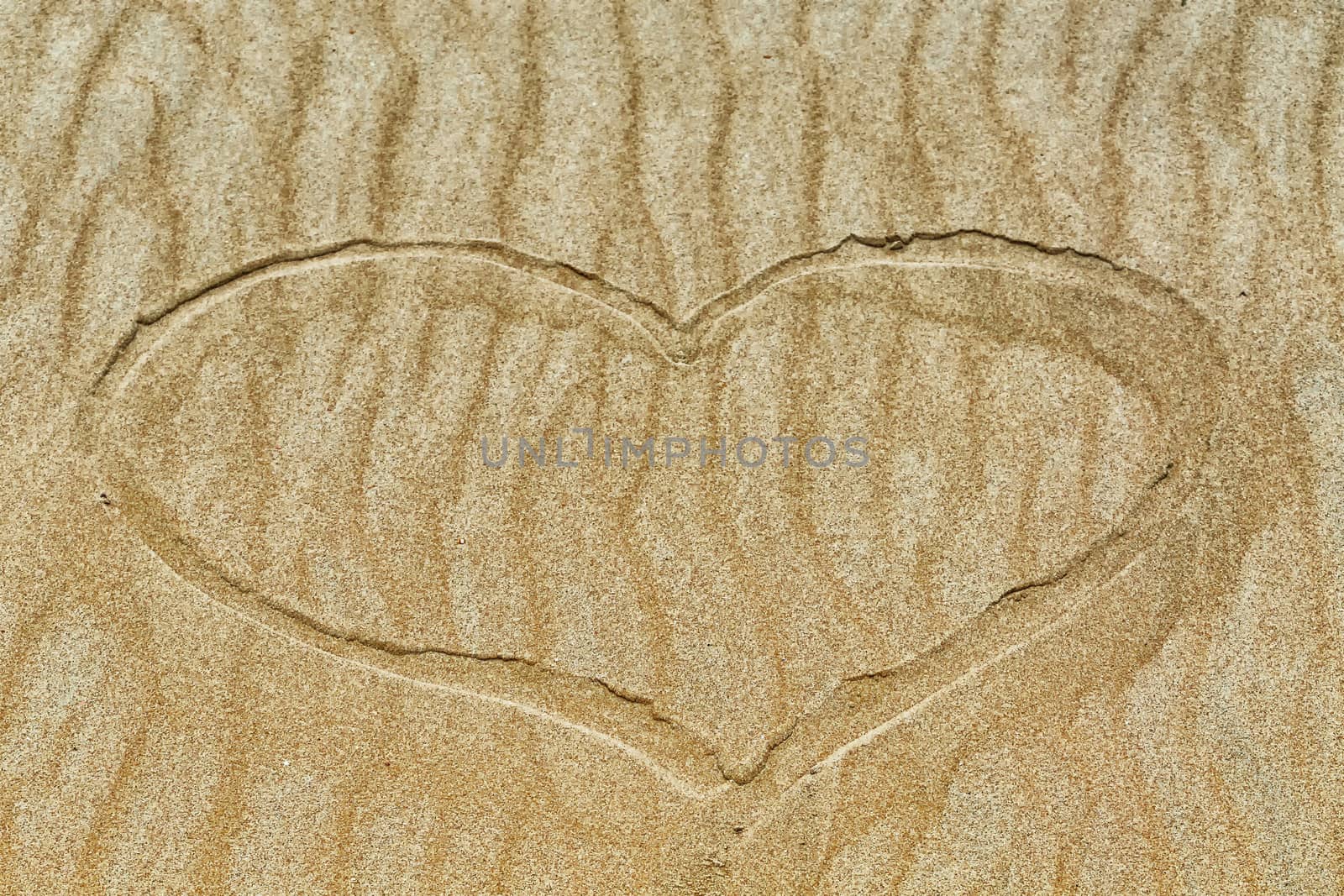 Golden sand with a subscribed in the sand heart.