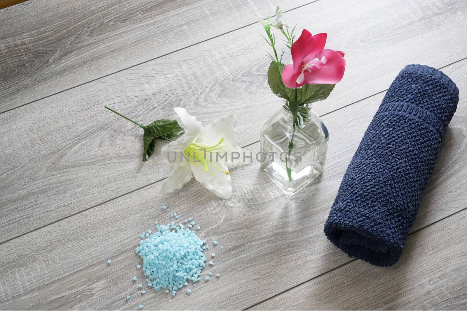 a bottle of massage oil, salts and a towel on the table