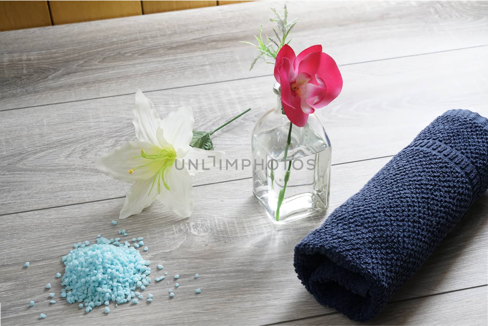 a bottle of massage oil, salts and a towel on the table