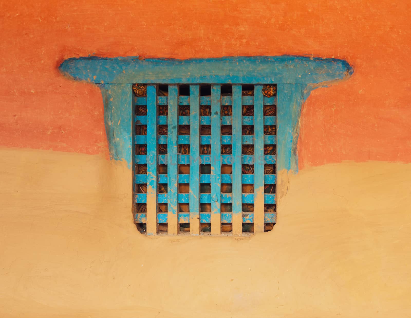 Traditional wooden Nepalese window called Ankhi jhyal. Painted blue on orange and ocher mud wall.