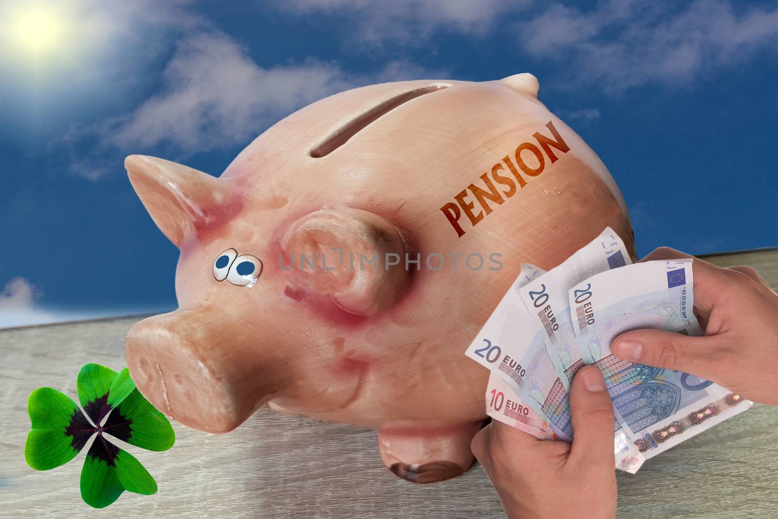 Piggy bank, lucky pig with lettering Pension stands on wooden surface in front of blue sky background.
