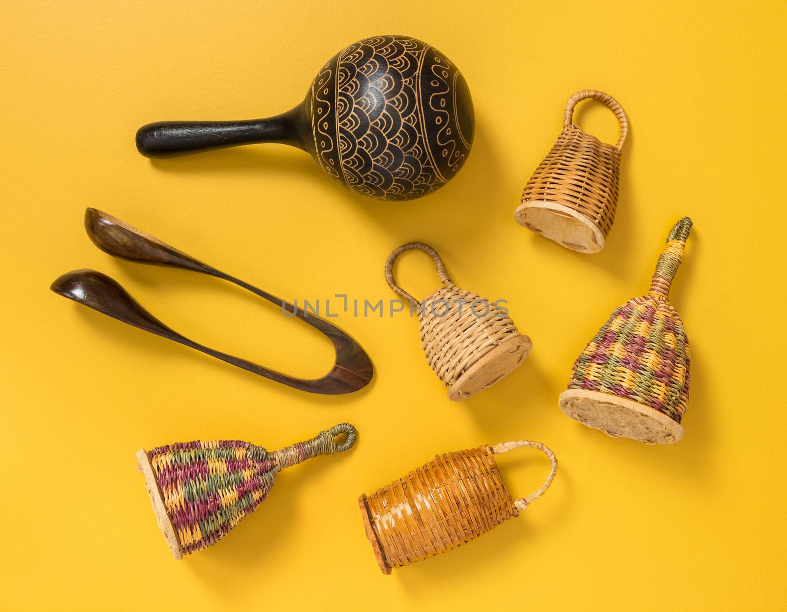 Traditional percussion musical instruments on yellow background. Caxixi shakers, maracas and musical spoons. 