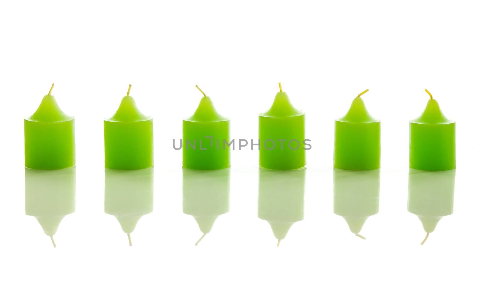 Green candles, with reflection, isolated on white background.