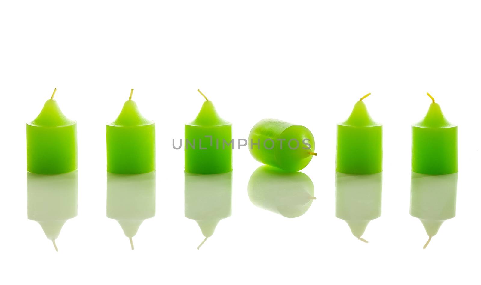 Row of green candles, with one laying down. With reflection, isolated on white background.