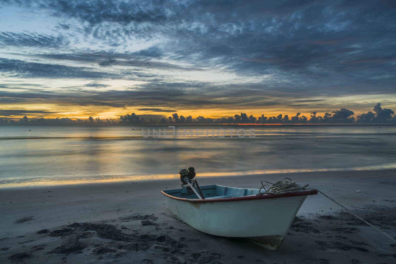 A beautiful tropical dawn with a boat on beach.