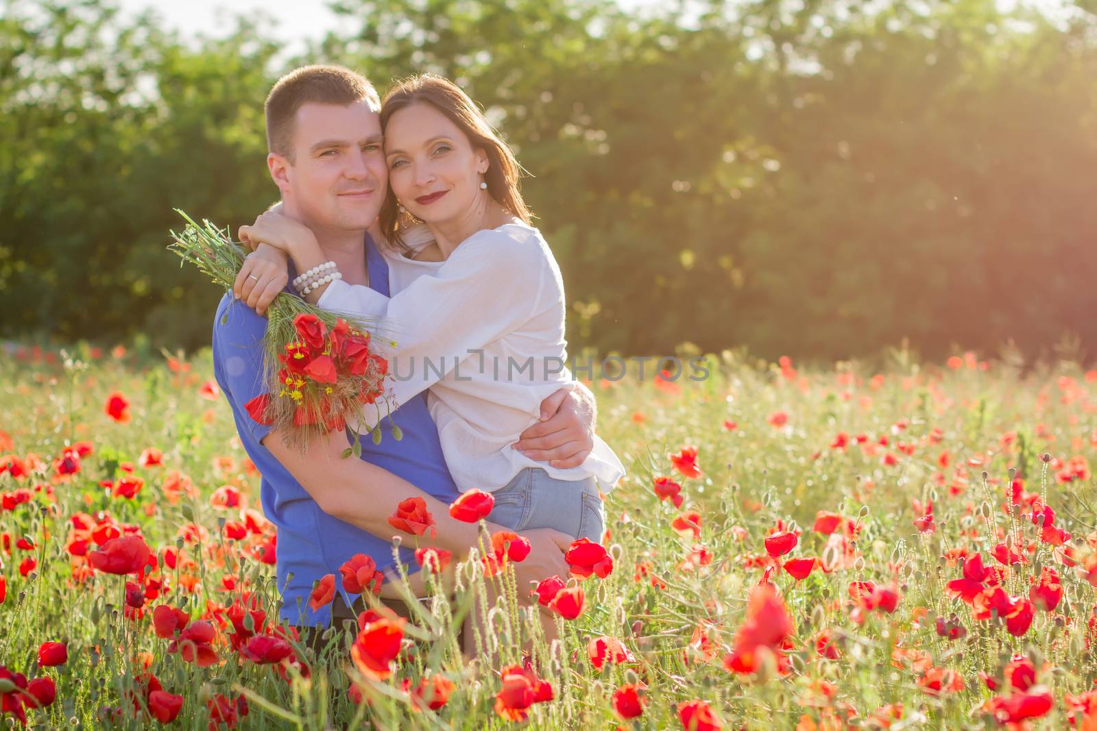 Couple among poppy field embracing and smiling nose-to-nose
