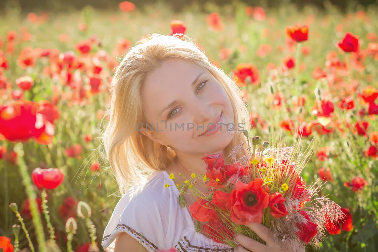 Woman with bouquet among poppies field at sunset by Angel_a