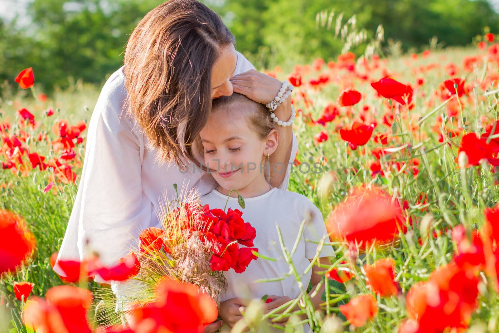 Mother brunette in a white dress with daughter together on blossoming red poppies field by Angel_a