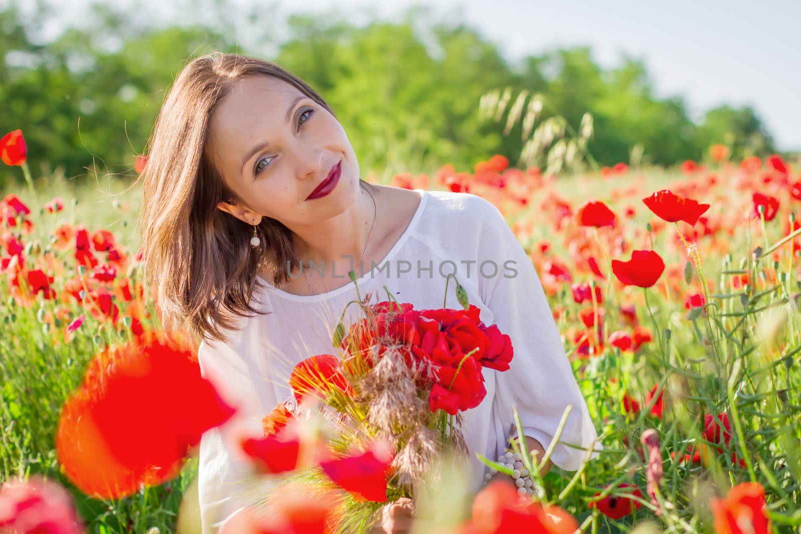 Woman with bouquet among poppies field at sunset by Angel_a