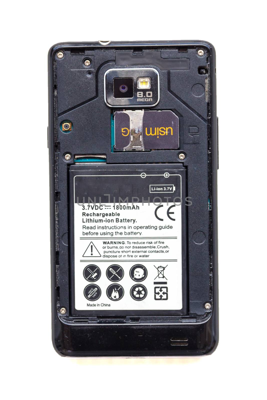 Back view of old smartphone with open cover isolated on white background. The battery and sim card are visible.