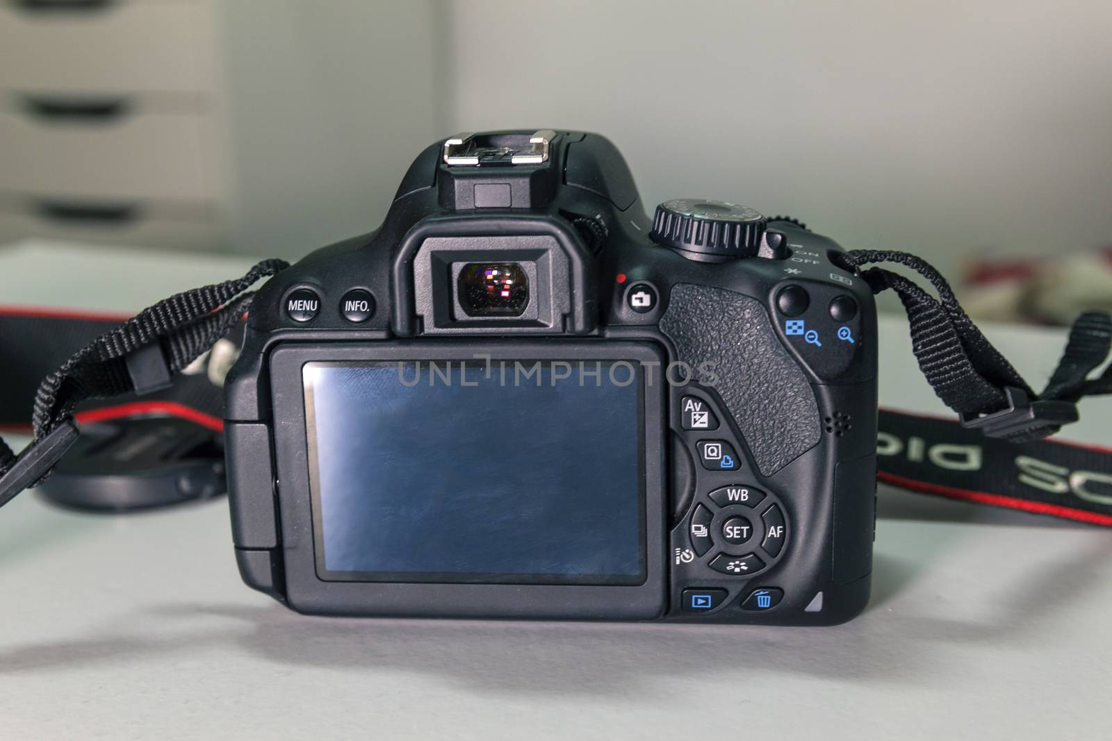 Closeup of modern black DSLR camera on white table.