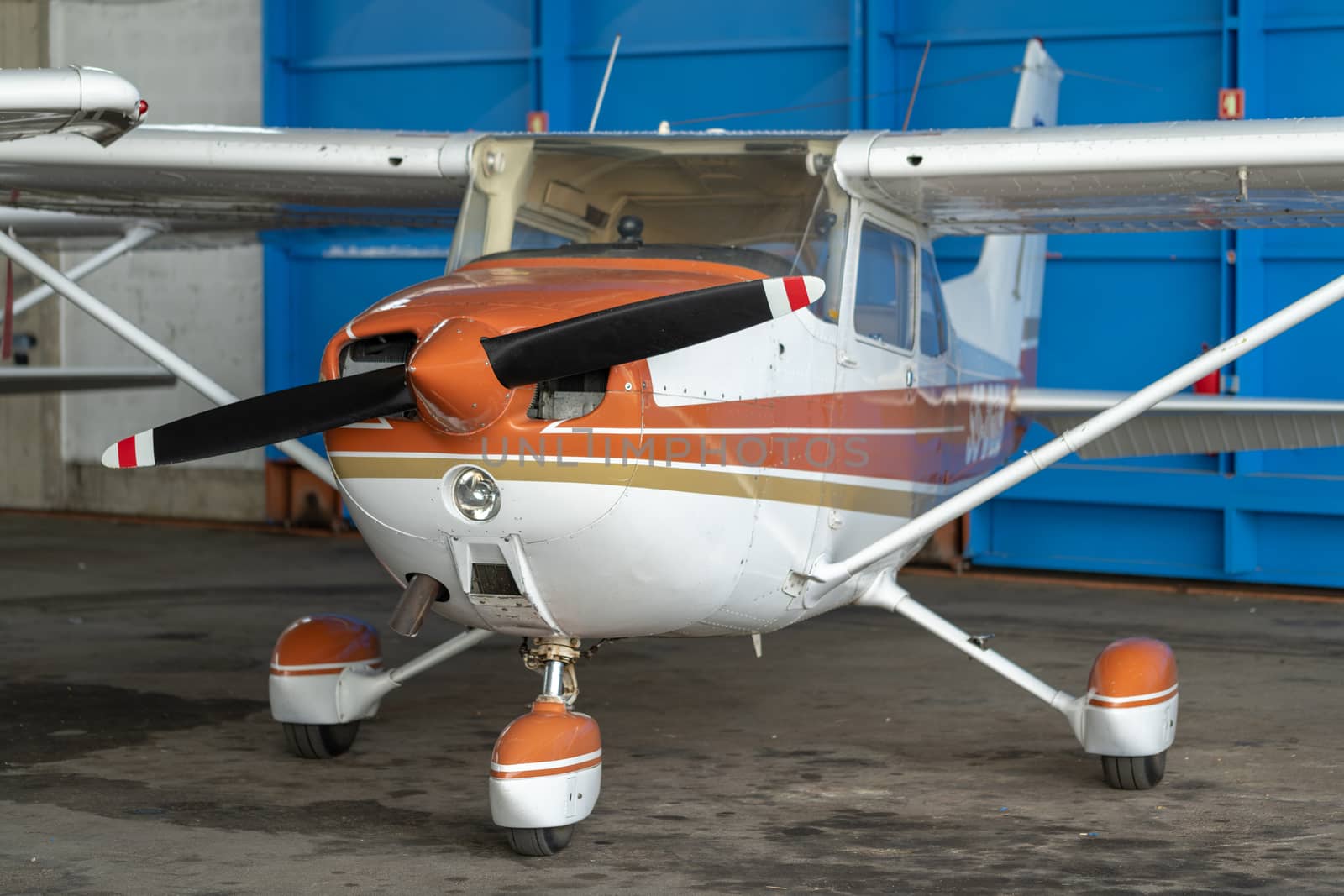 Small Sport Aircraft parked in hangar, close up. detail view of front, nose, cowling and propeller, piston aircraft