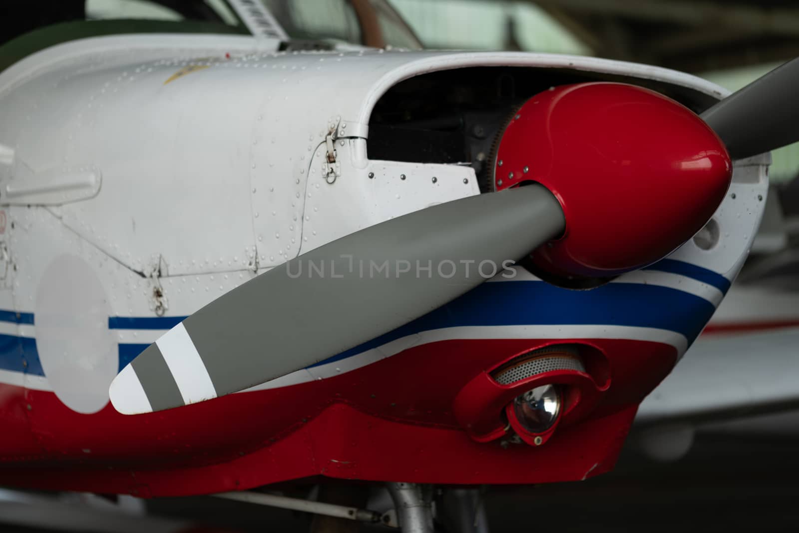 Small Sport Aircraft parked in hangar, close up. detail view of front, nose, cowling and propeller, piston aircraft