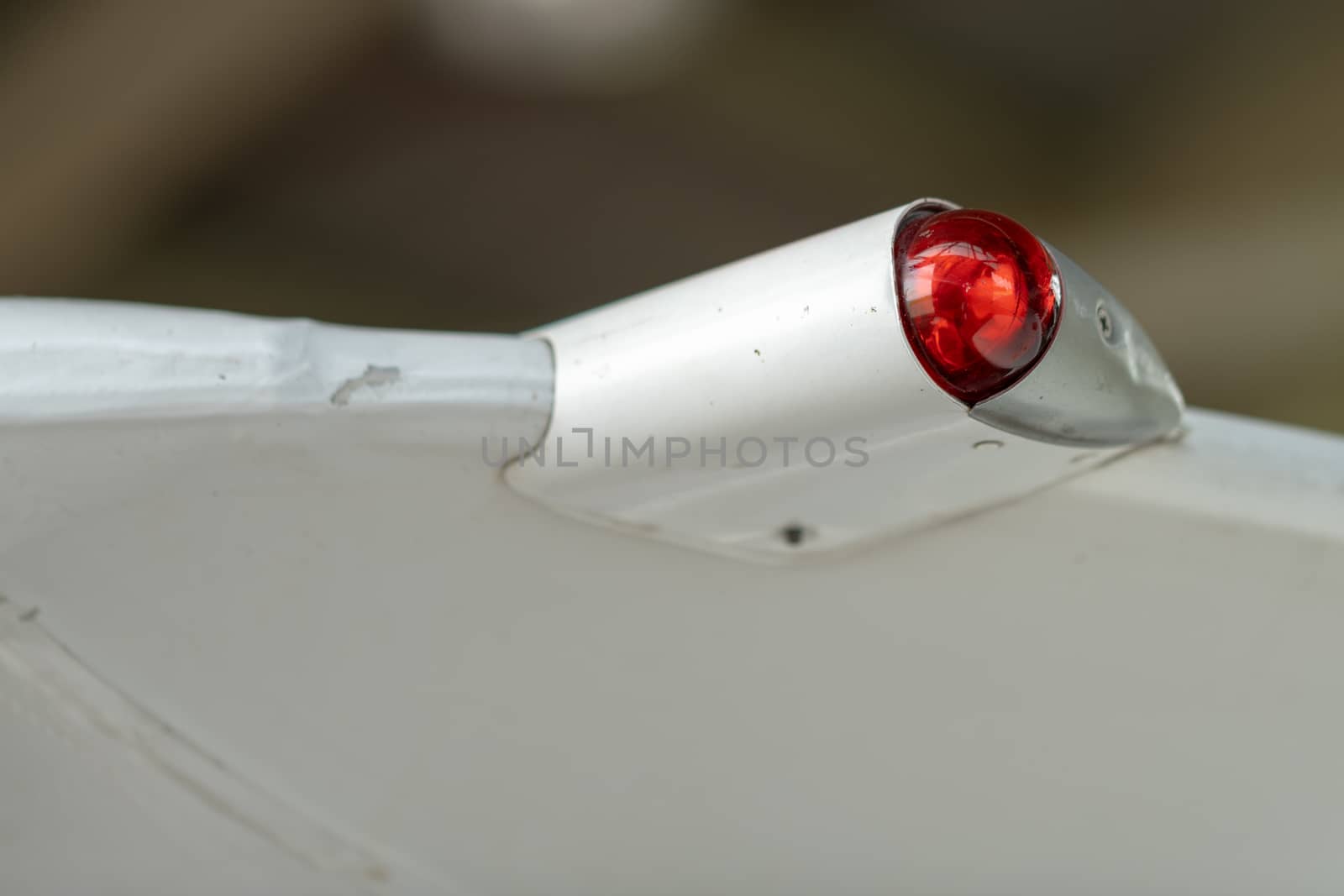 Wing of an airplane with red position light by asafaric