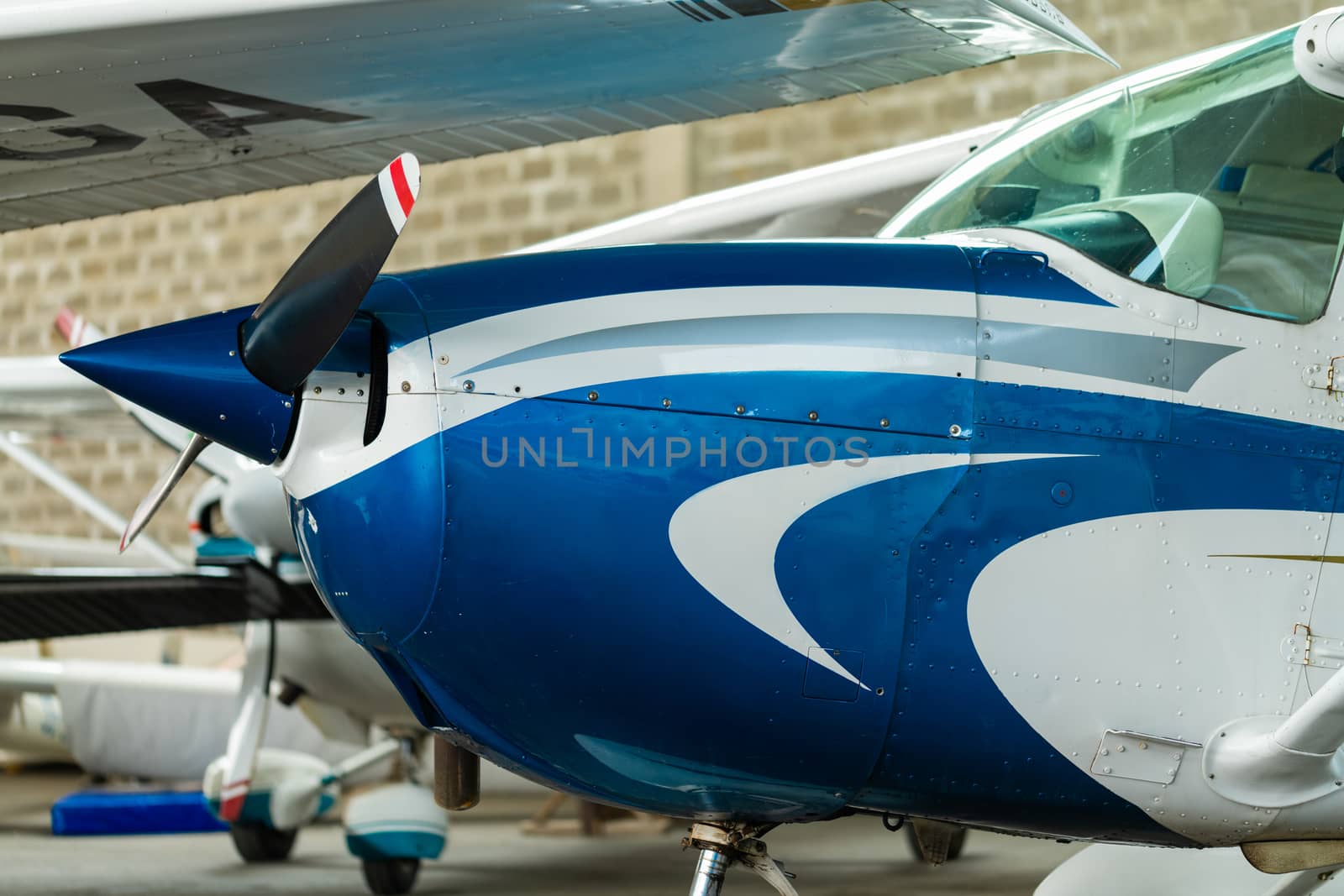 Small Sport Aircraft parked in hangar, close up. detail view of front, nose, cowling and propeller, piston aircraft