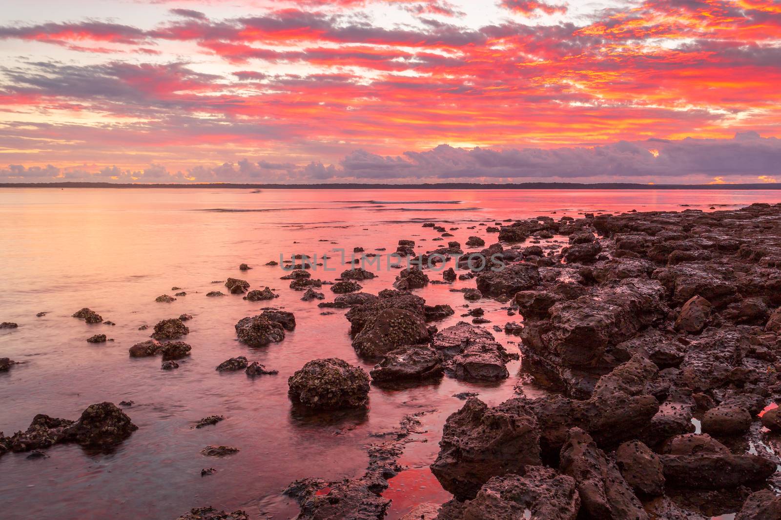 Rich red sunrise from the rockshelf at a small coastal township called Callala Bay a tranquil setting and suitable mooring for boats and yachts too.