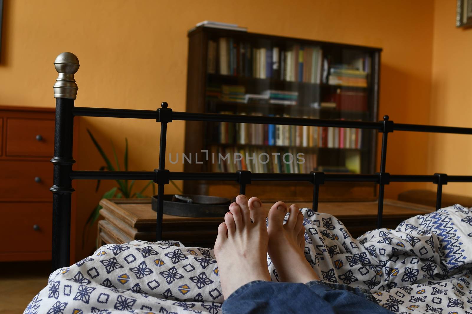 Men feet alone in a bed. Men's feet. Colored background. Close up.