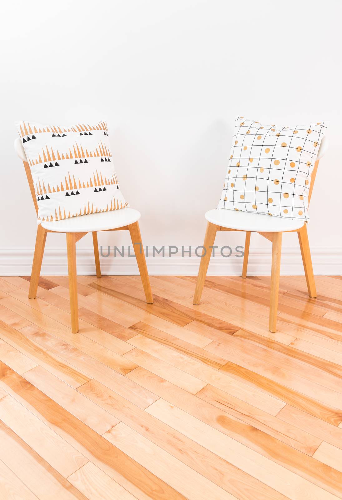 Stylish chairs with ornamental cushions on hardwood floor by anikasalsera