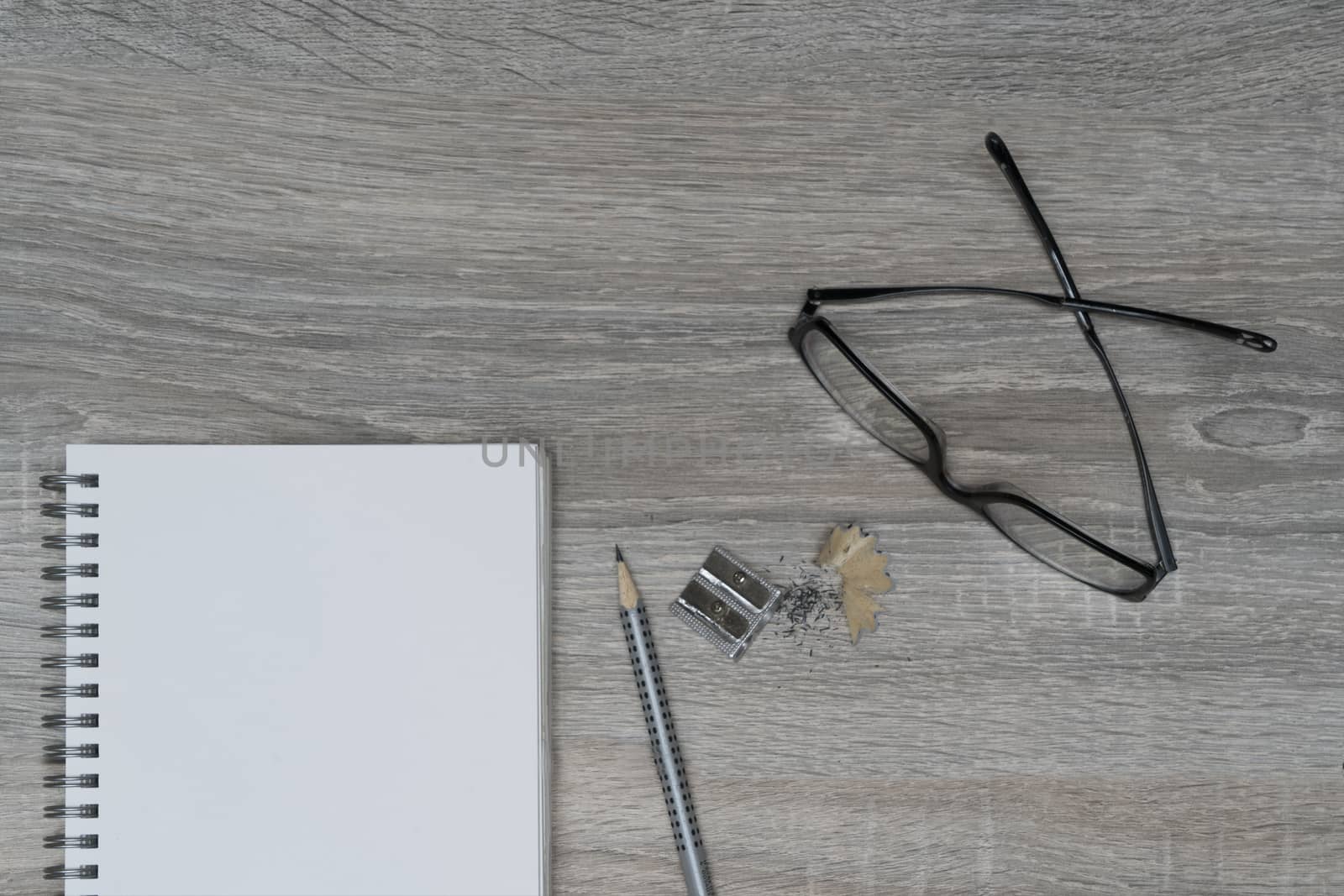 the desk with glasses, a pencil and a clipboard