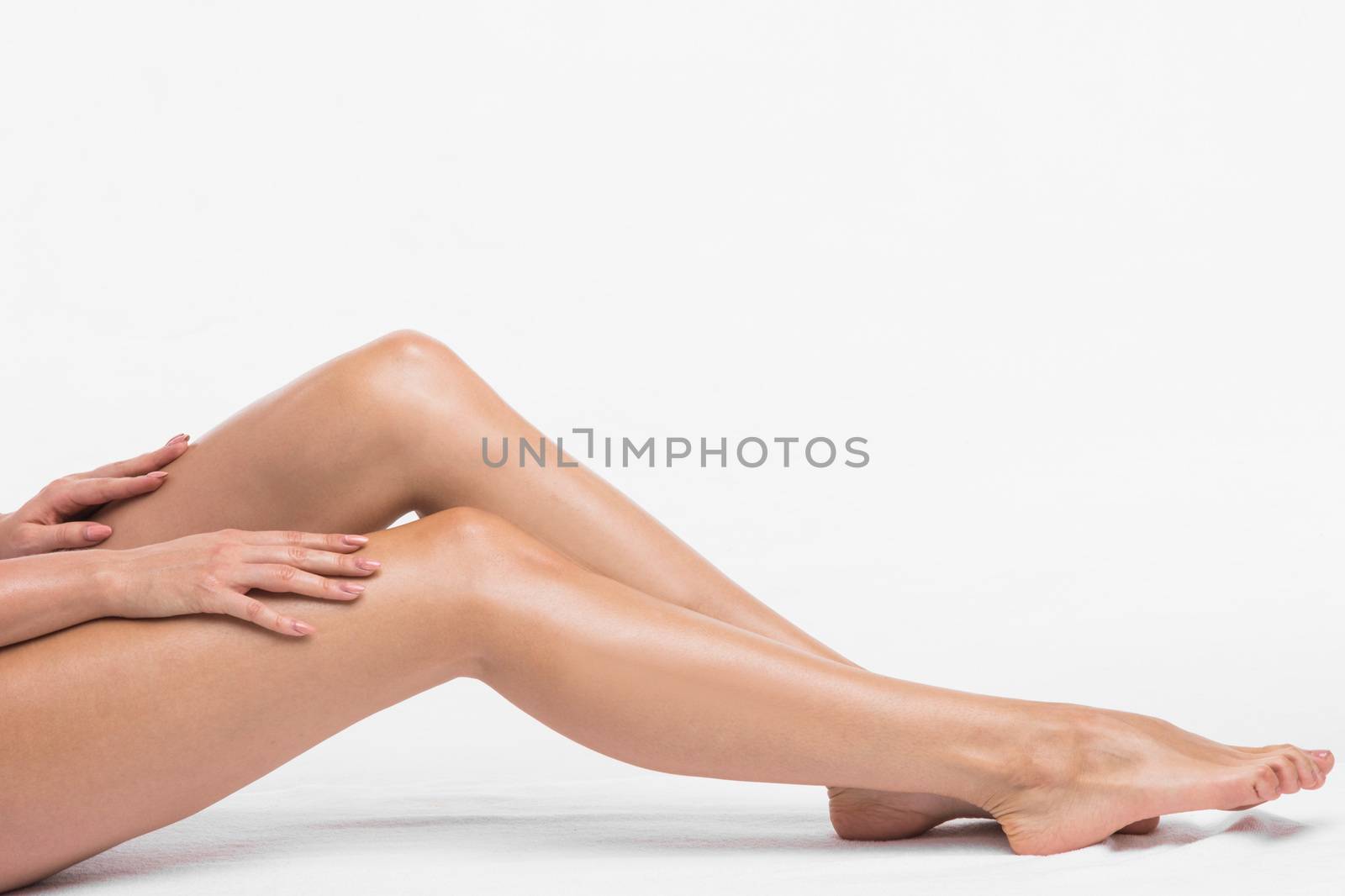 Beautiful female legs touched by hand, white background