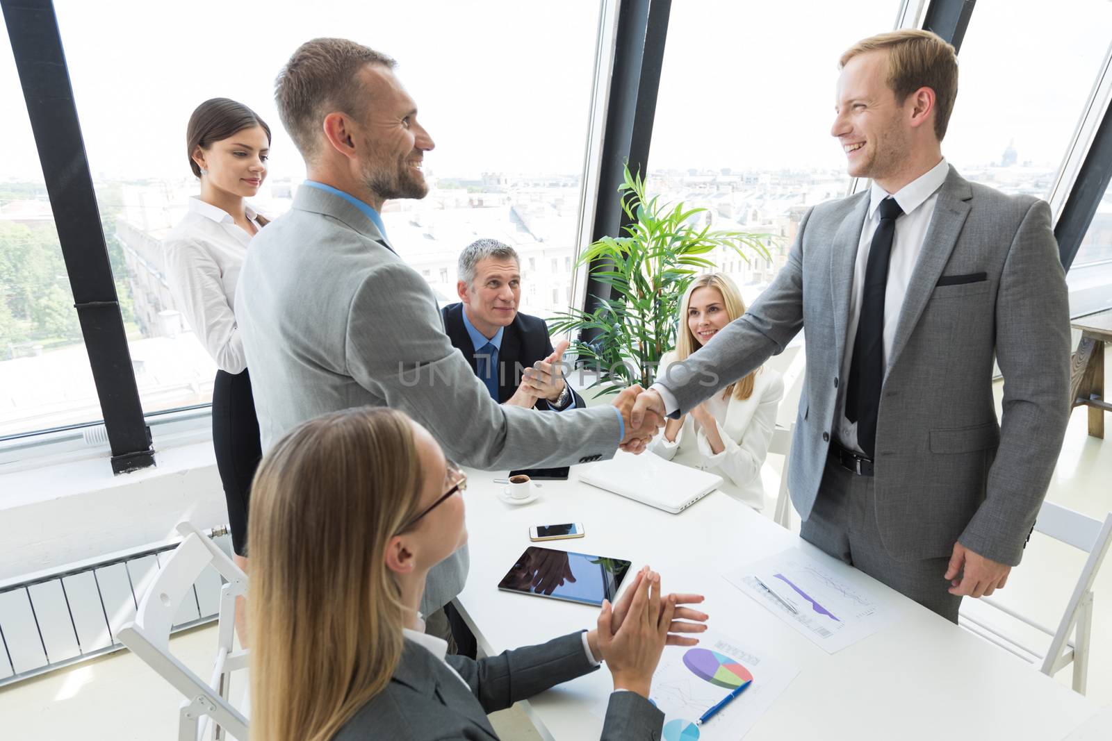 Businessmen shaking hands at meeting in office, business team clapping