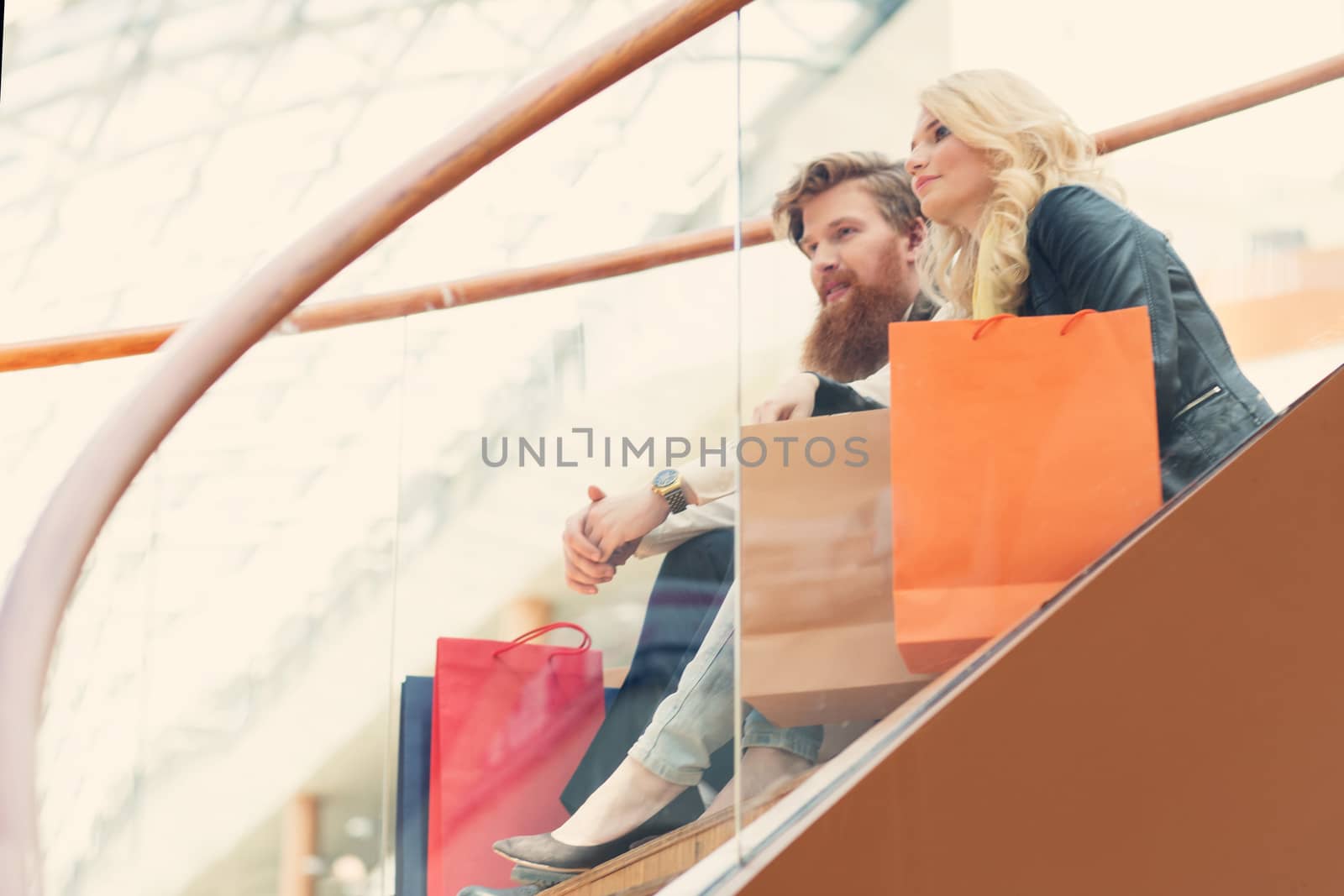 Happy beautiful young couple with shopping bags in mall