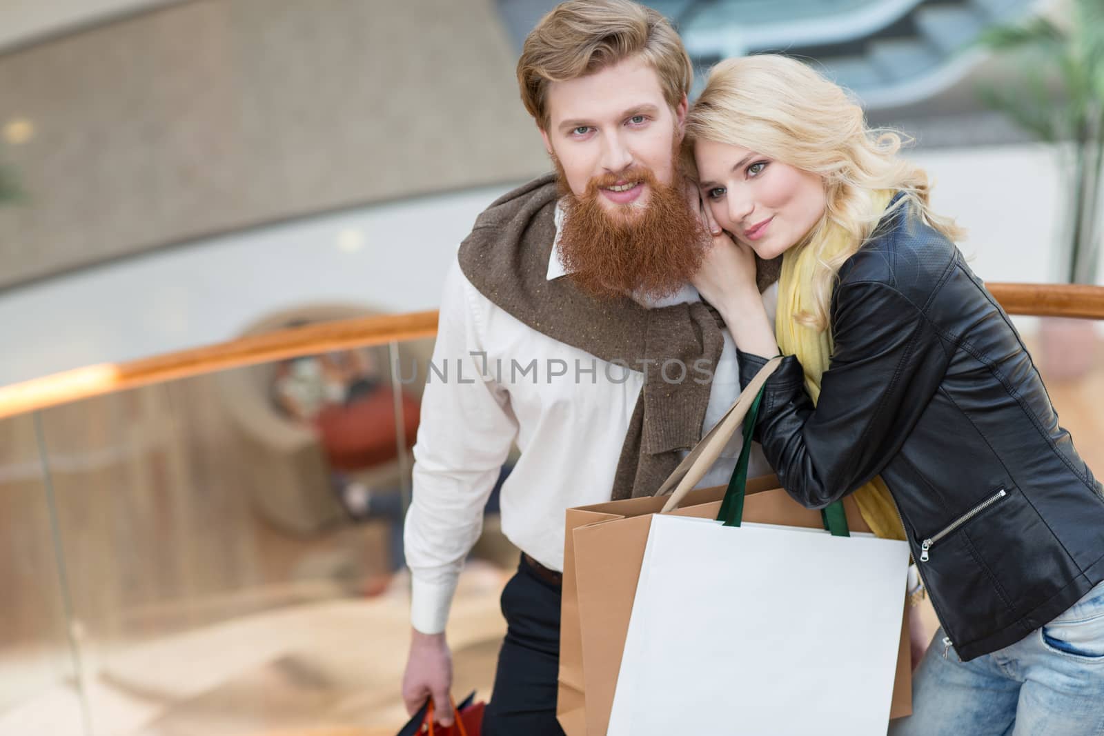 Happy beautiful young couple with shopping bags in mall