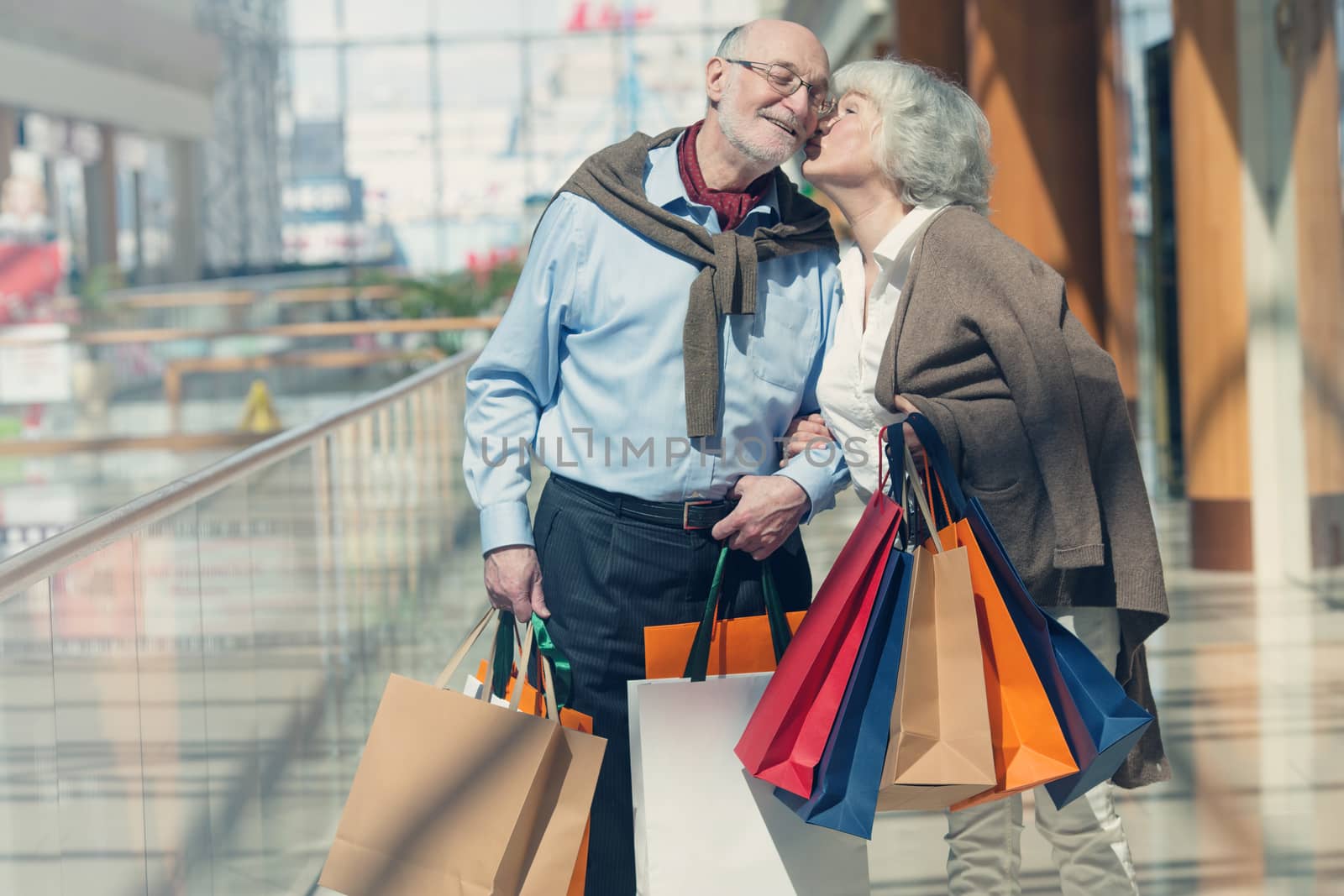 Adult senior couple with purchases in bags at shopping mall