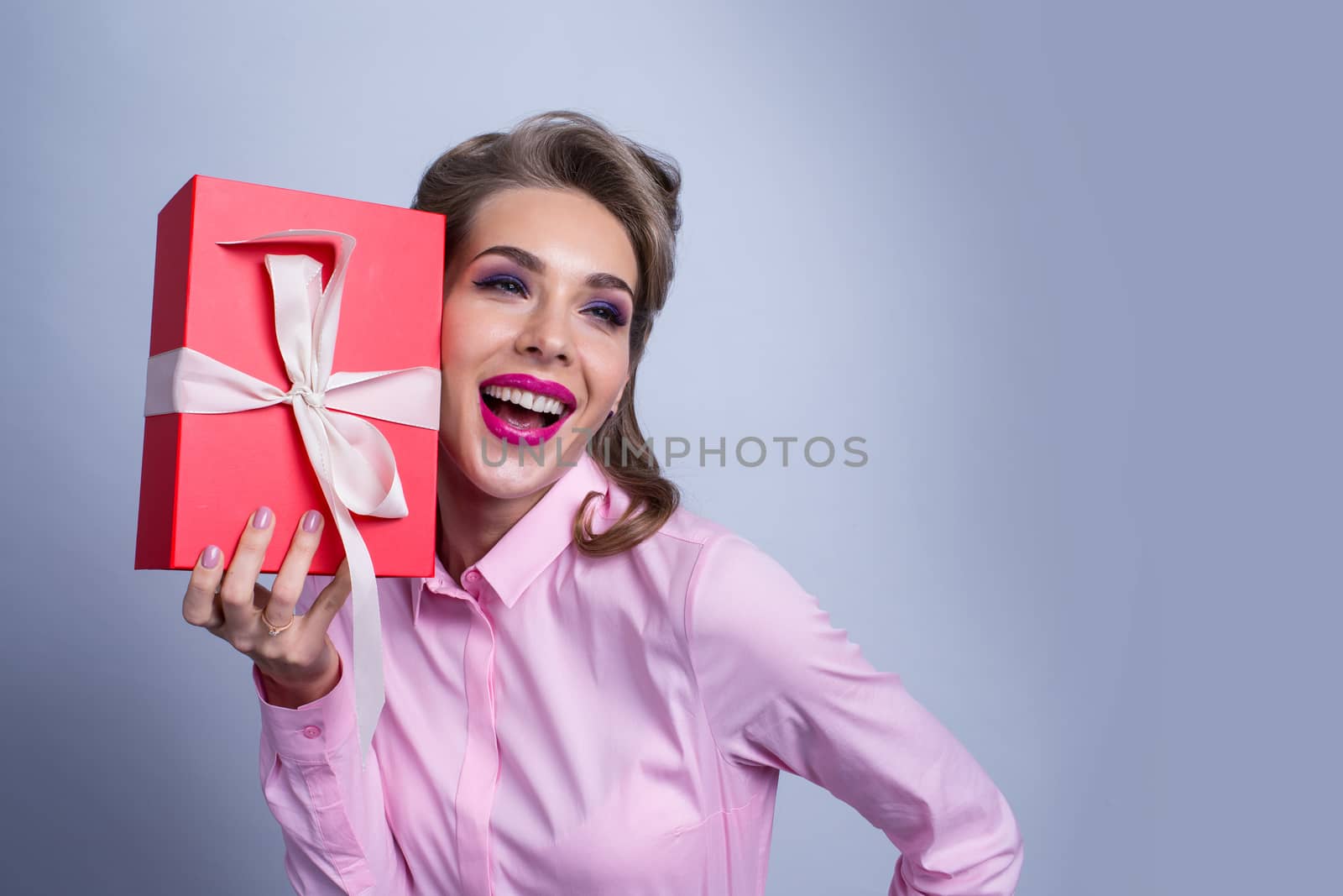 Happy beautiful funny woman holding gift box, listening