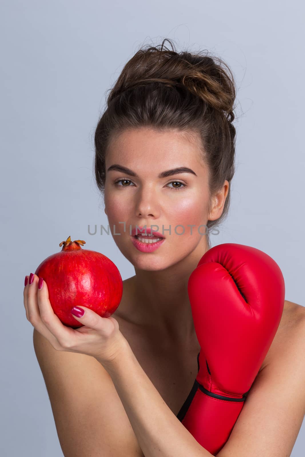 Young Woman with pomegranate and boxing glove, fighting for healthy eating concept