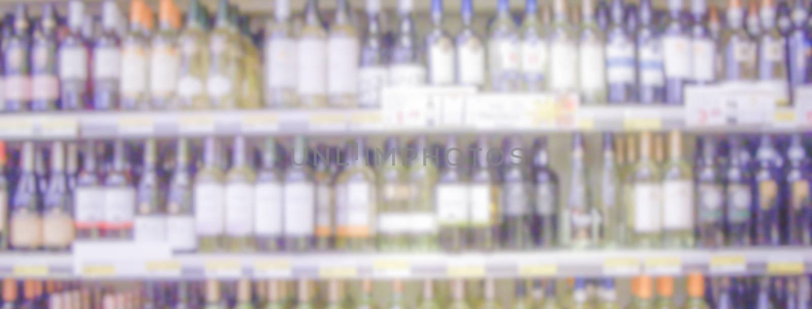 Defocused background of shelves with wine bottles in a supermark by marcorubino