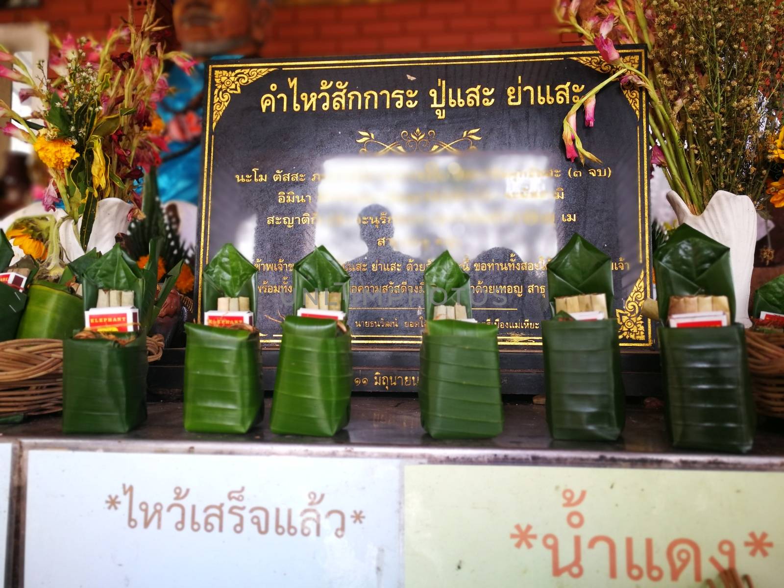 incense candles flowers cigarettes and  ceramic dolls  for Buddha statue and Thailand text were words to pray god