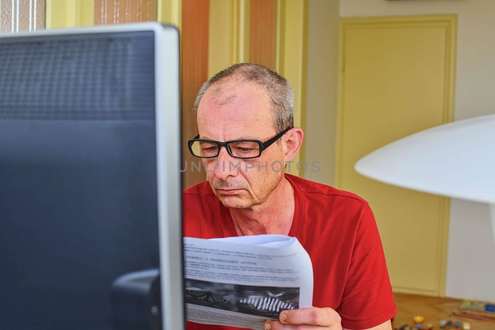 Middle aged man with glasses sitting at desk. Mature man using personal computer. Senior concept.  Man and paperwork. Pensive man  working at home office. 