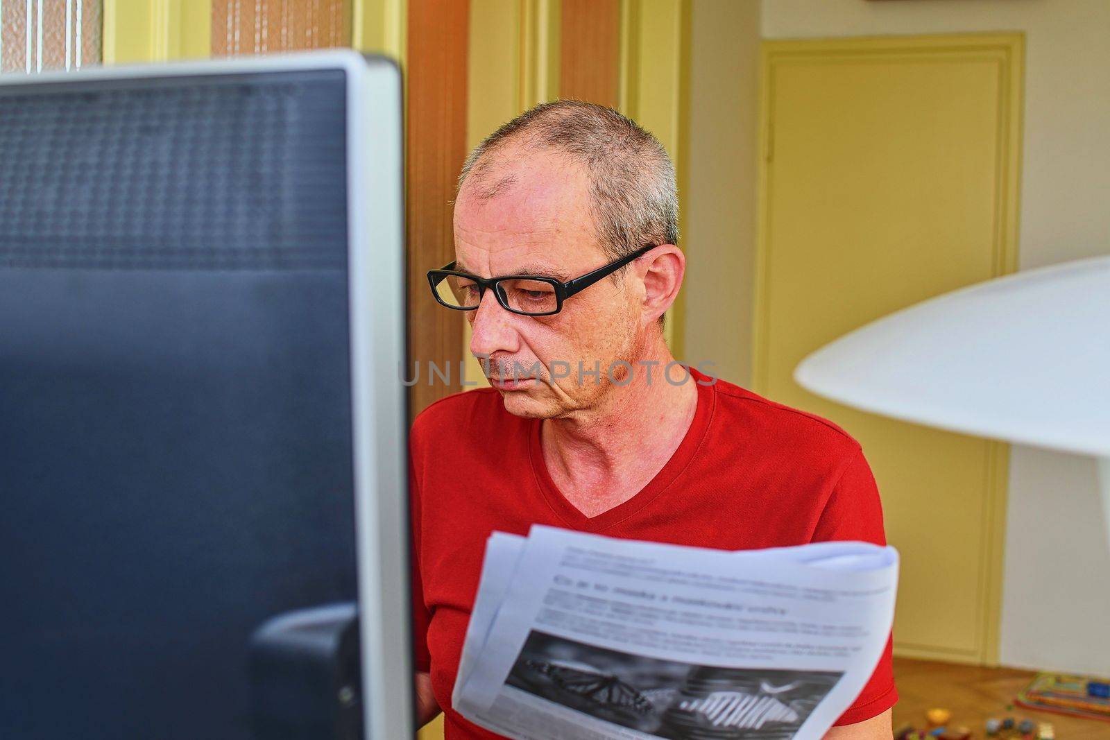 Middle aged man with glasses sitting at desk. Mature man using personal computer. Senior concept.  Man and paperwork. Pensive man  working at home office. 