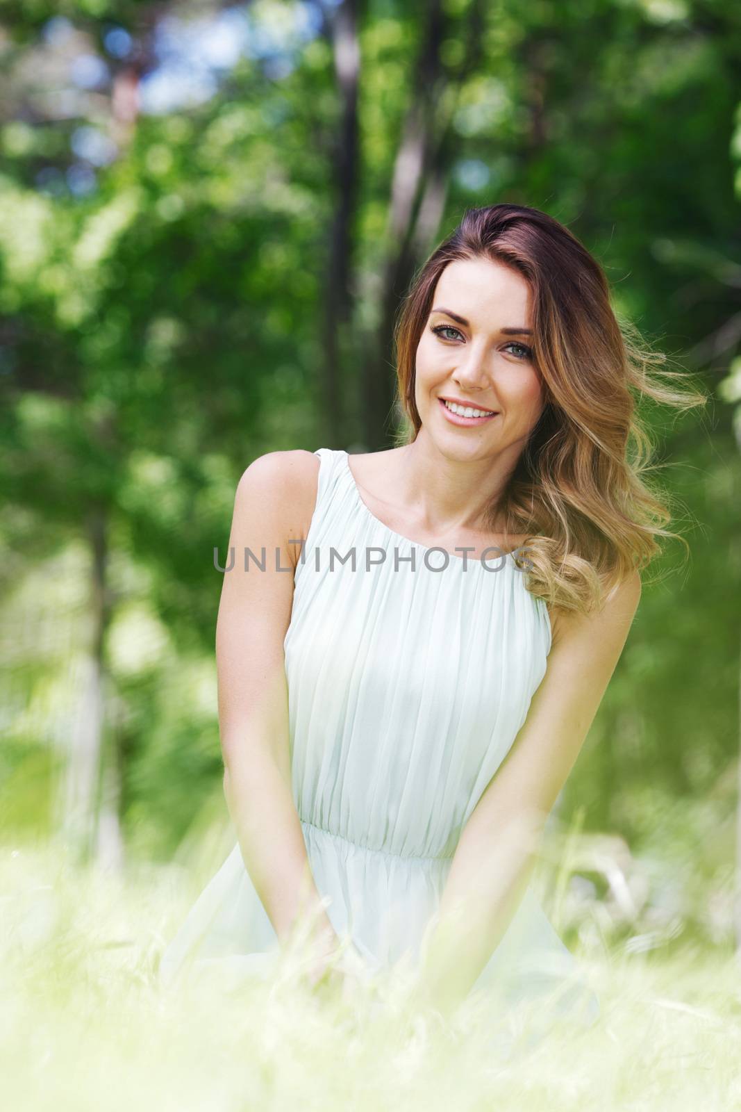 beautiful young woman in blue dress sitting on grass
