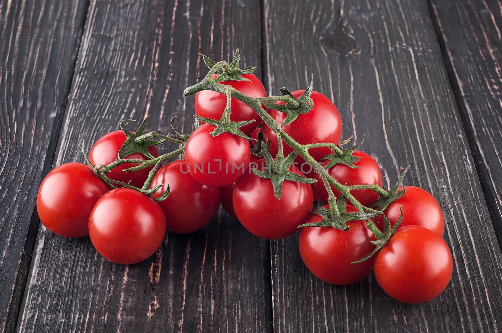 Branches cherry tomatoes on wooden table. Blurred background.