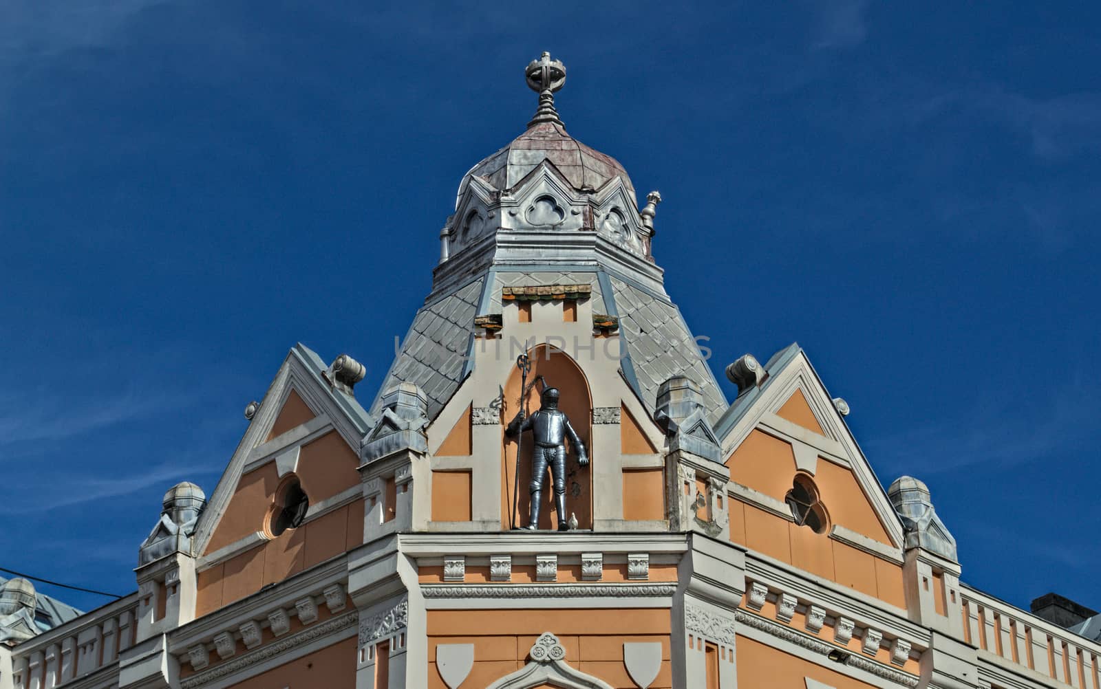 Top of old 19th century restored building with a knight armor in the middle