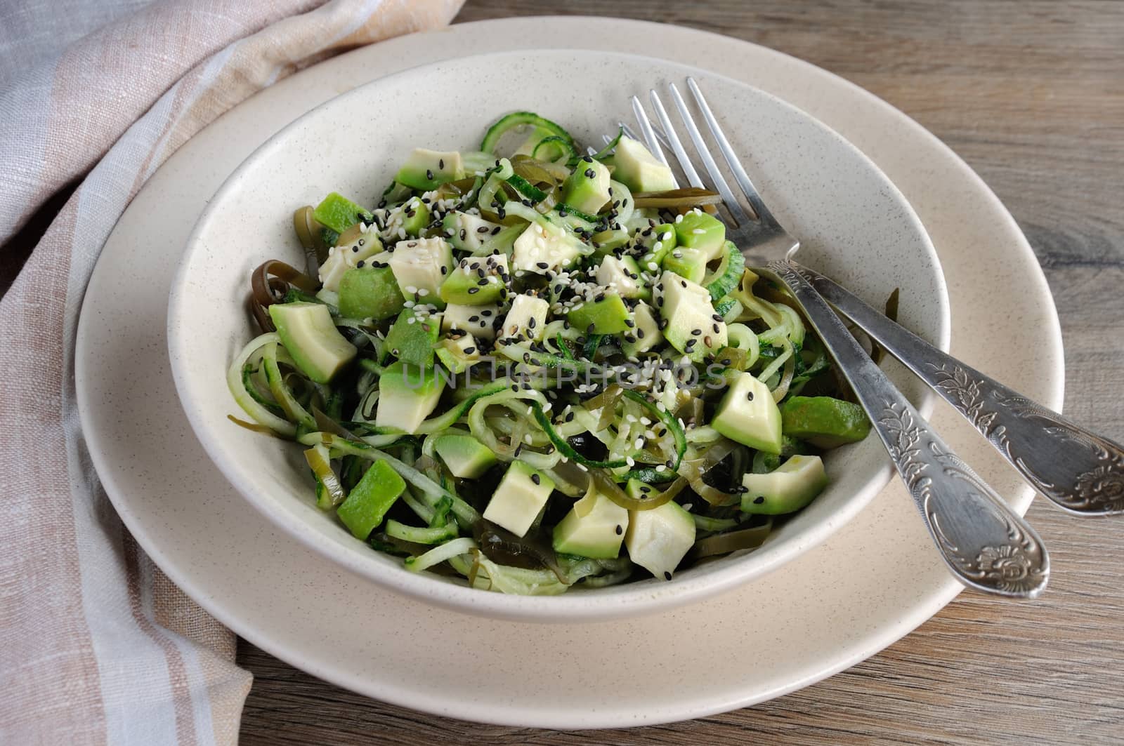 Salad from noodles from cucumbers and laminaria, slices of avocado with sesame