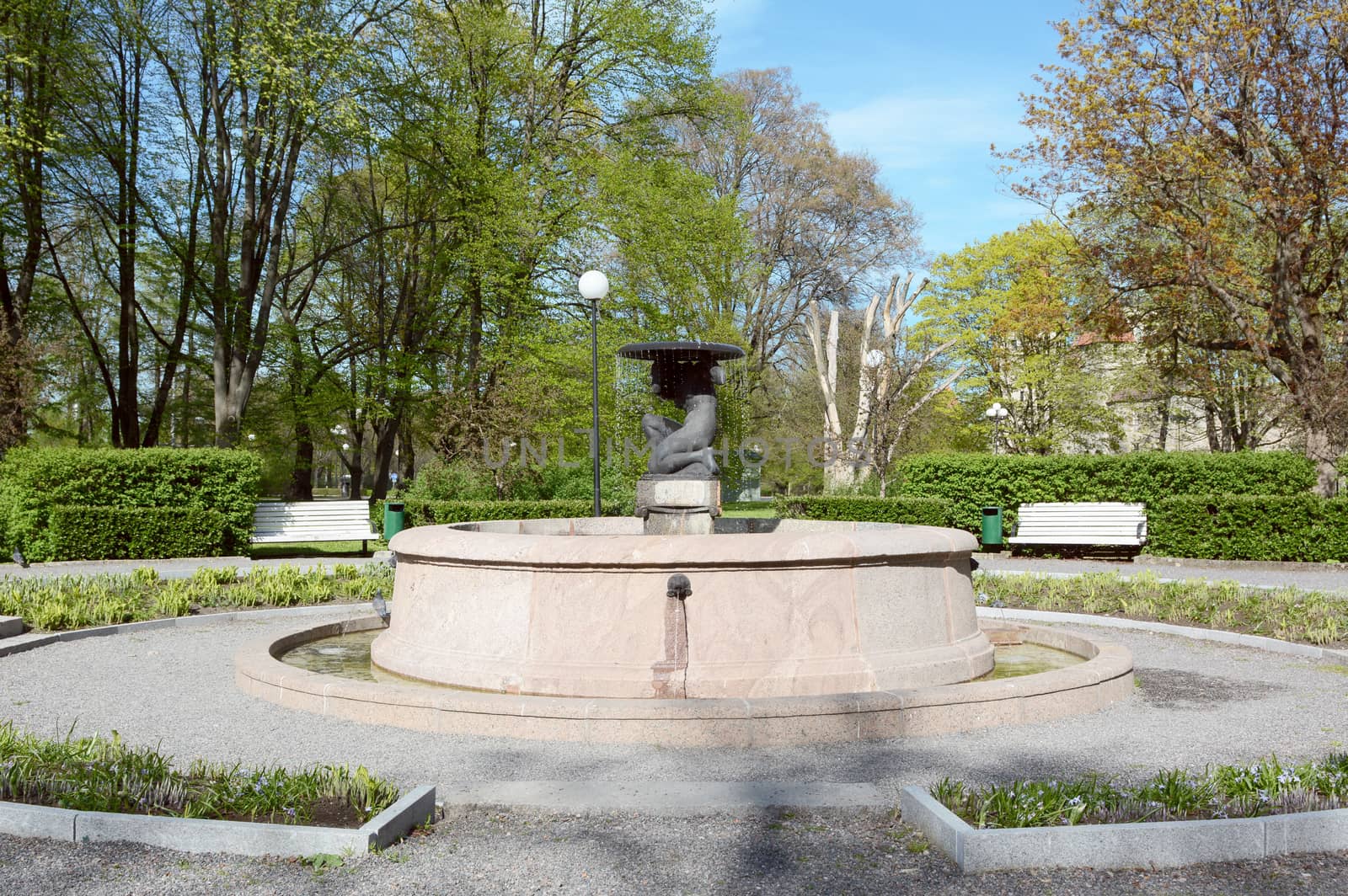 Fountain water feature in Tower's Square in Tallinn, Estonia, surrounded by diverse trees in spring 