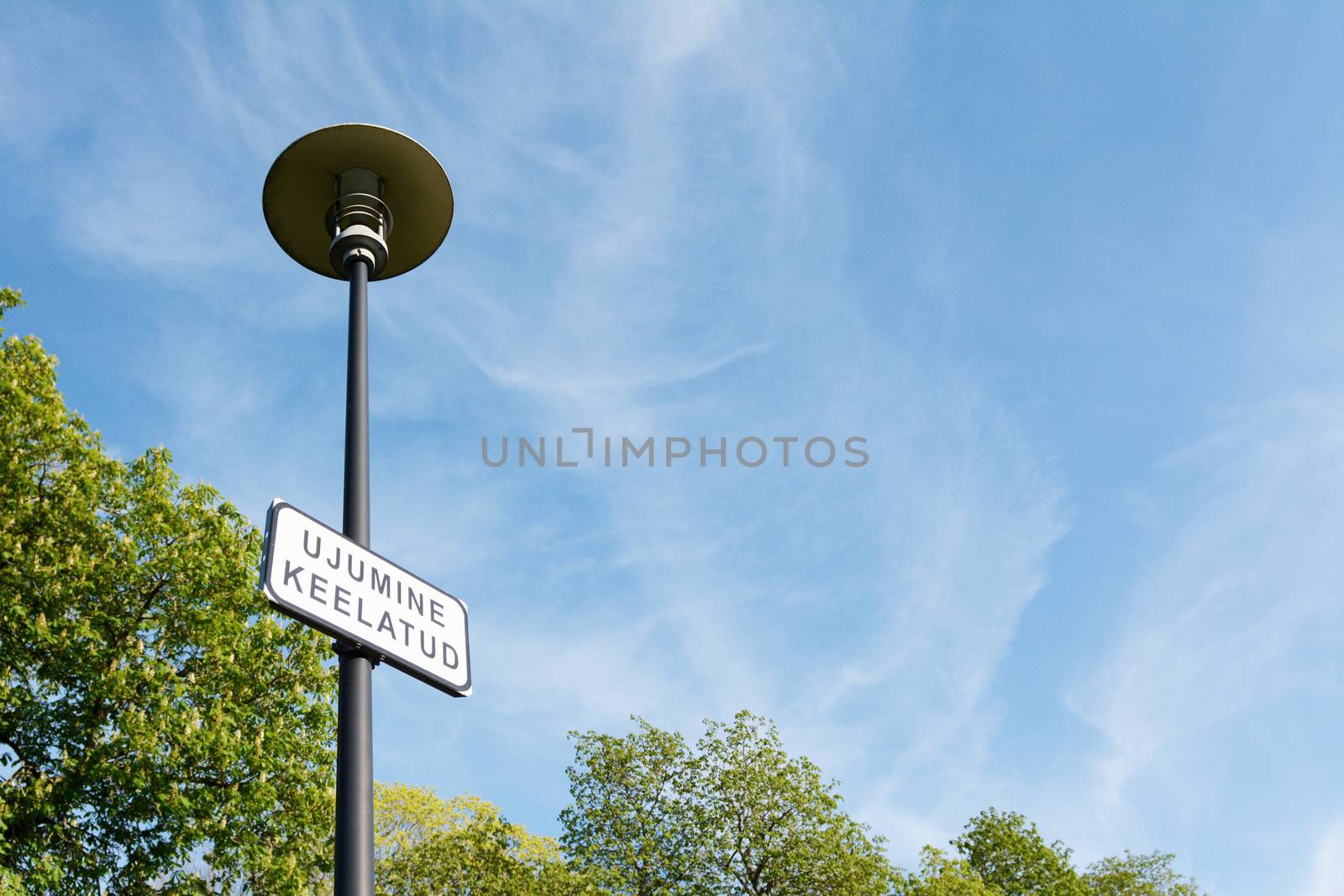 Notice on a lamp post in Estonian - swimming prohibited, against a blue sky