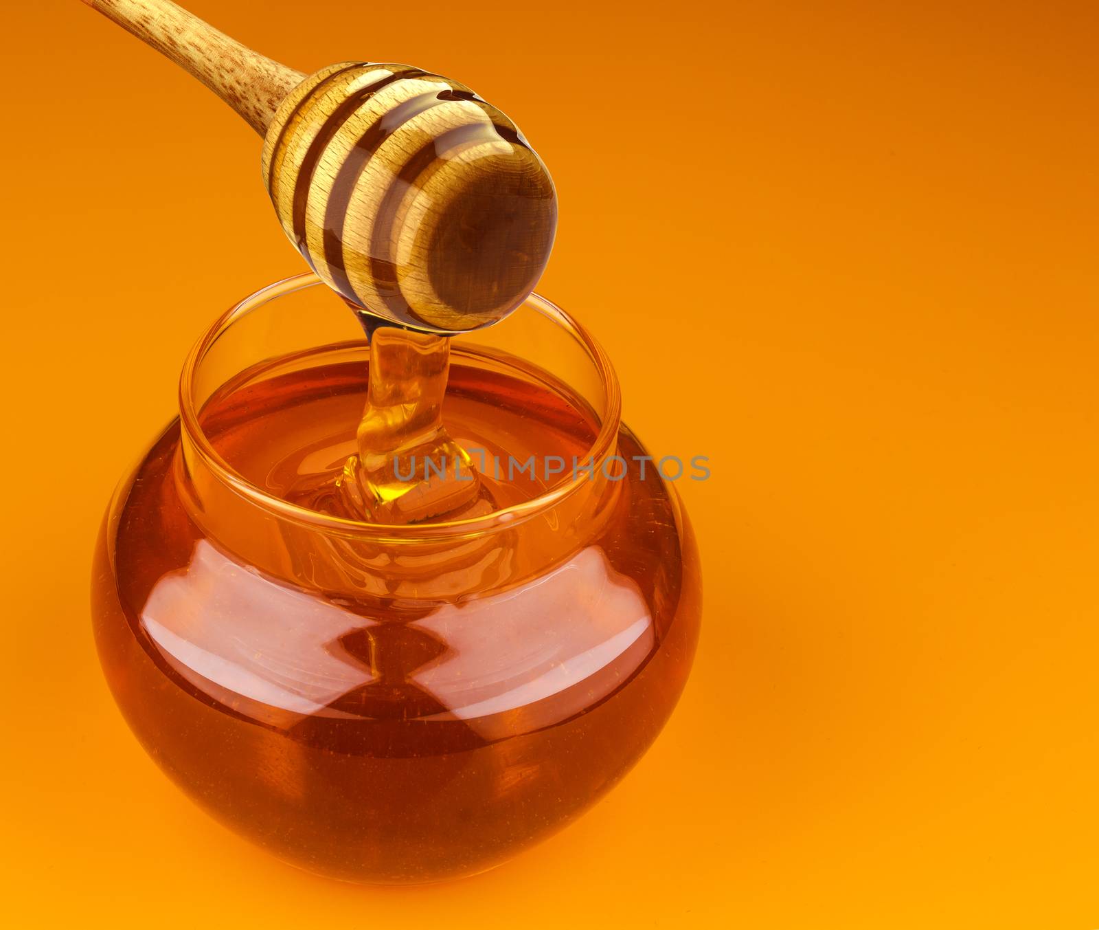 Honey stick and bowl of pouring honey isolated on yellow background with clipping path
