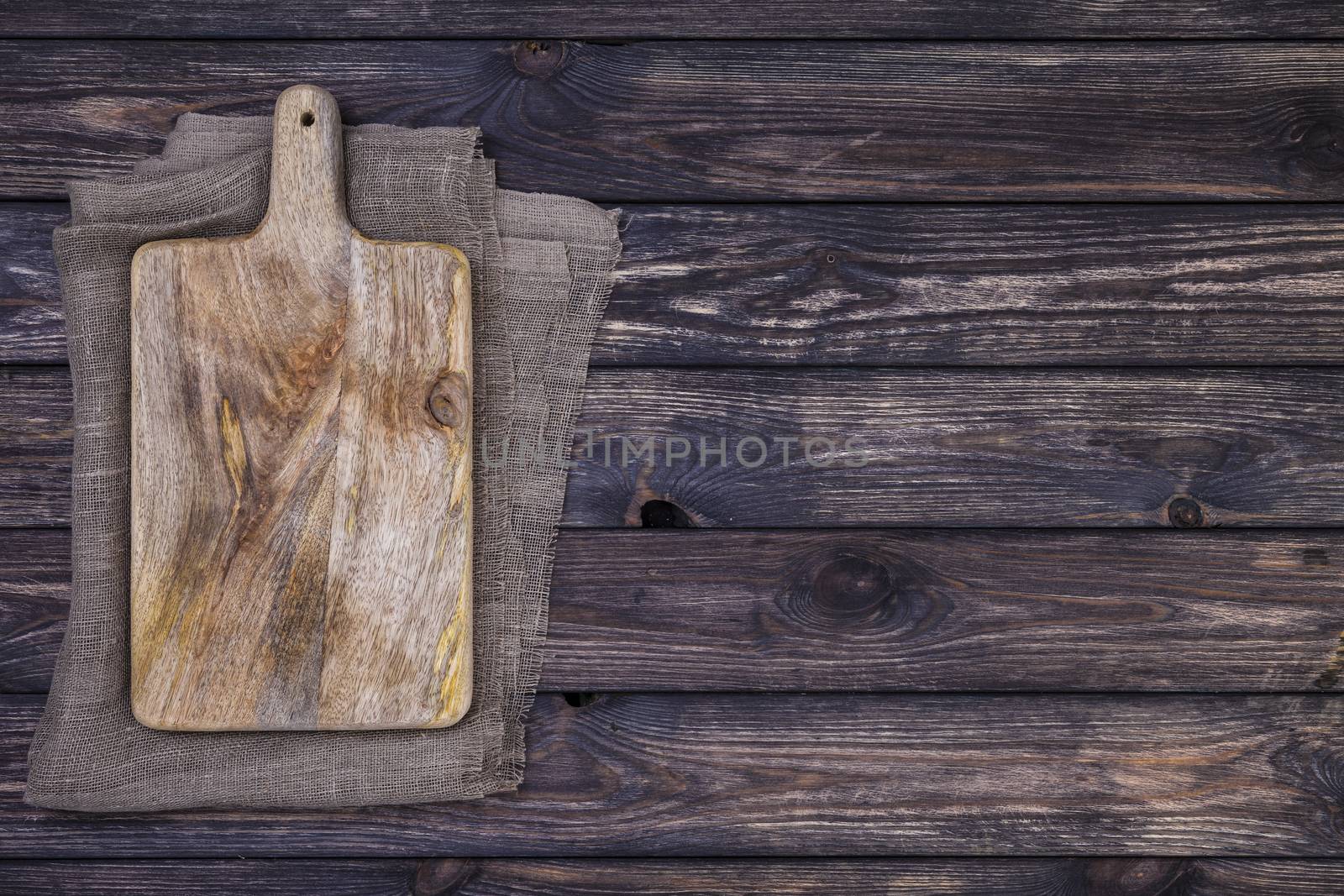 Old cutting board on dark wooden table. Top view. Copy space by xamtiw