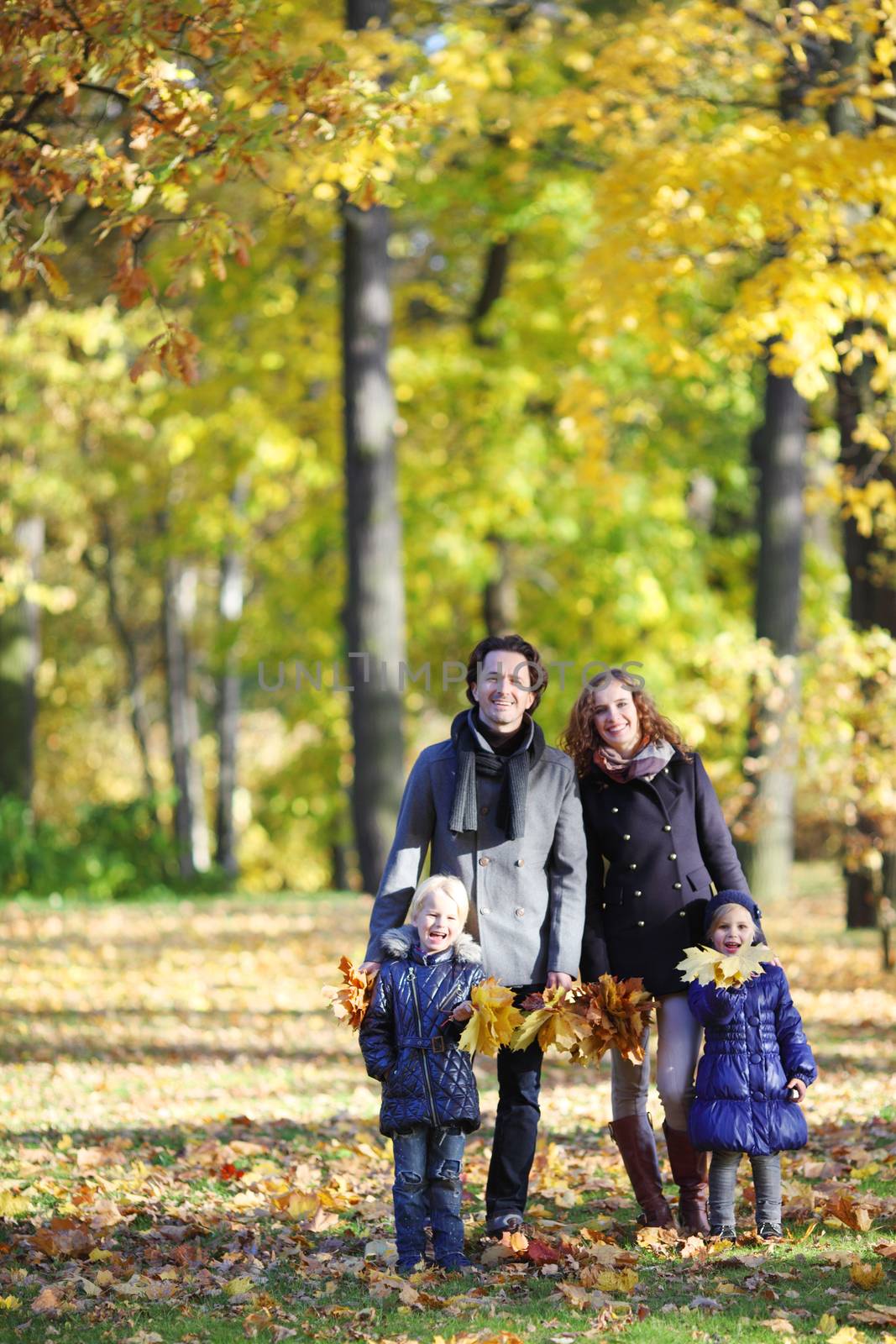 Family with children walking in autumn park by ALotOfPeople