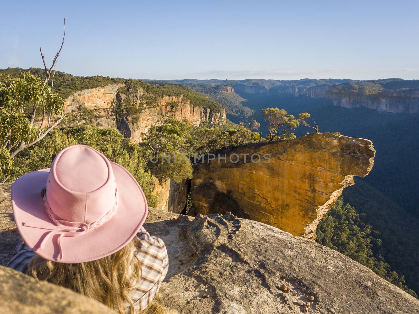 Woman relaxing after a lonk trek on the edge of the escarpment with stunning cliff top views of mountains and valleys