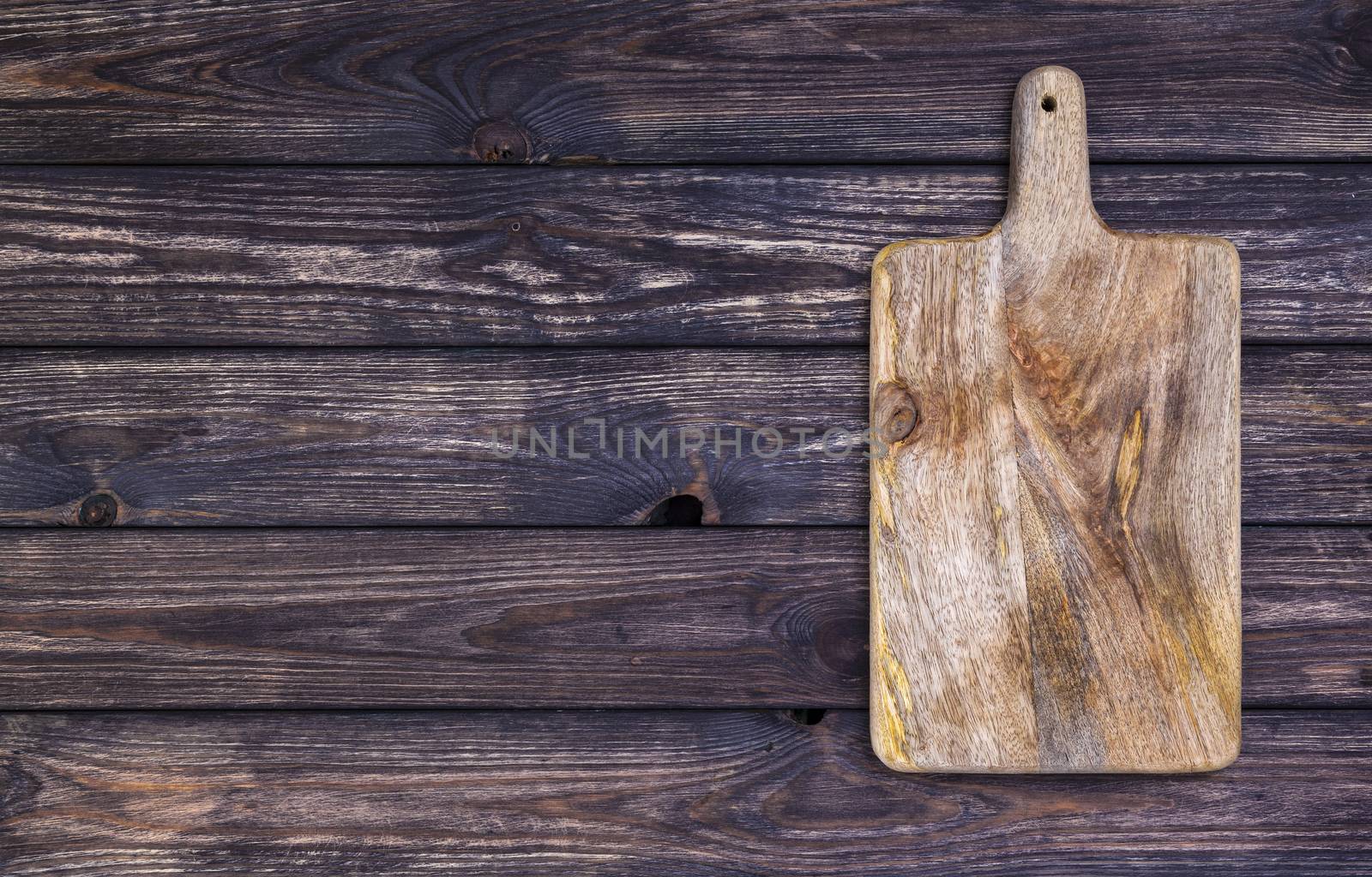 Cutting board on dark wooden table. Top view. Copy space