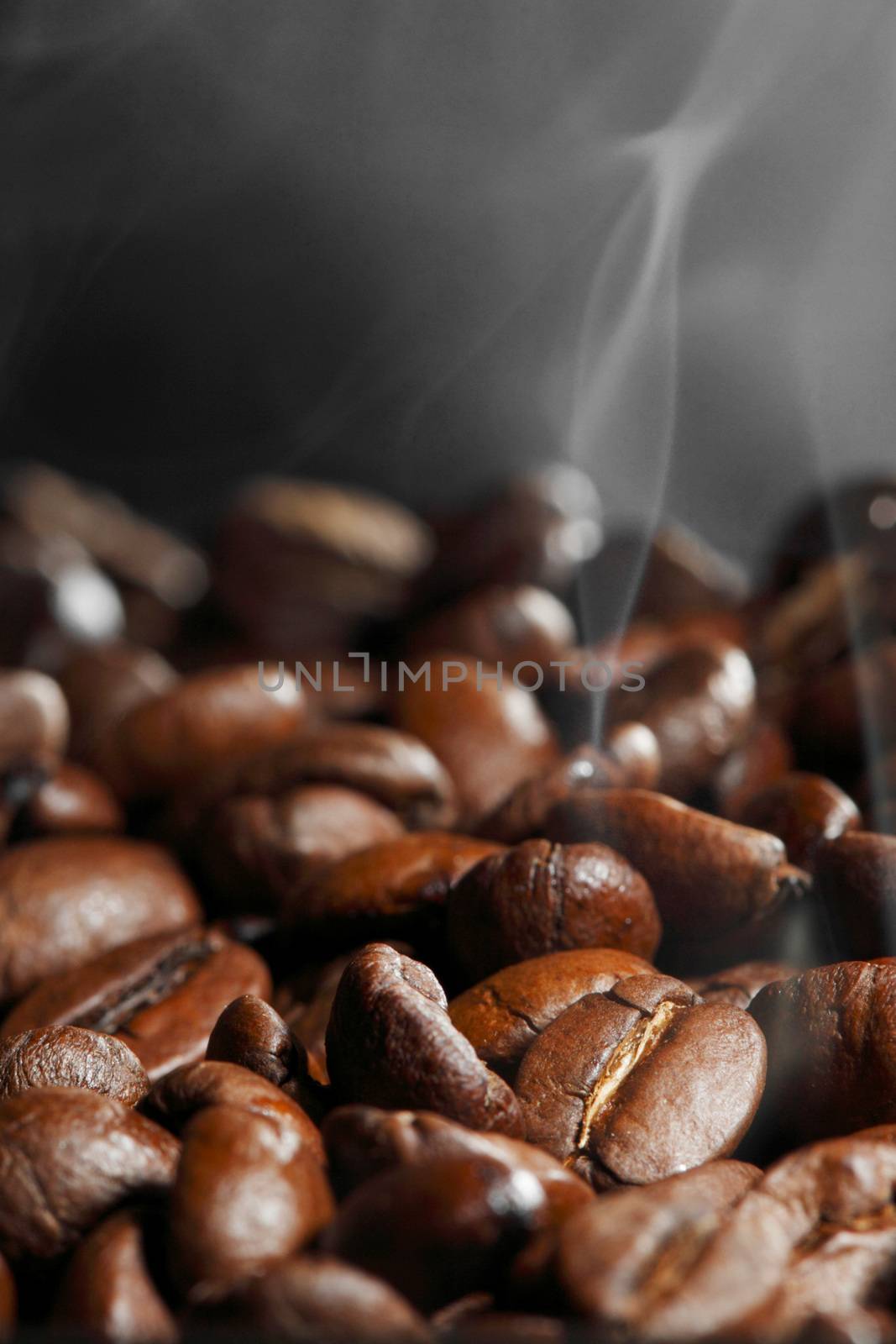 Hot roasted coffee beans and steam on black