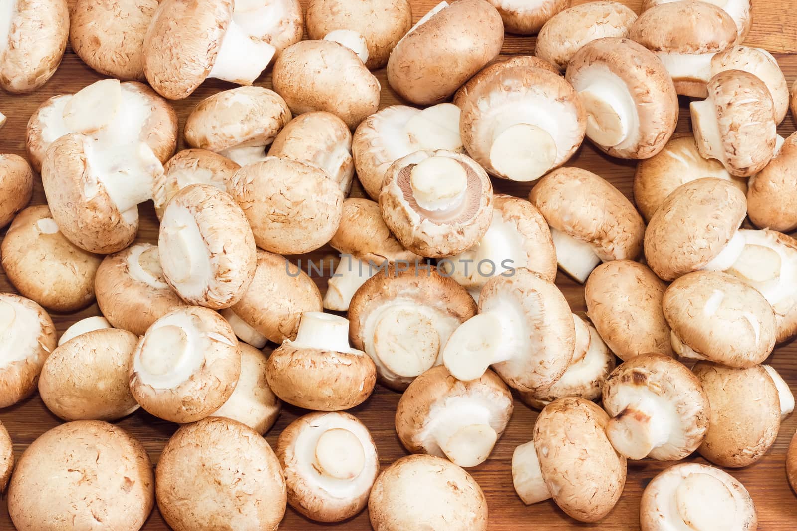 Background of the fresh whole uncooked button mushrooms closeup on a wooden surface
