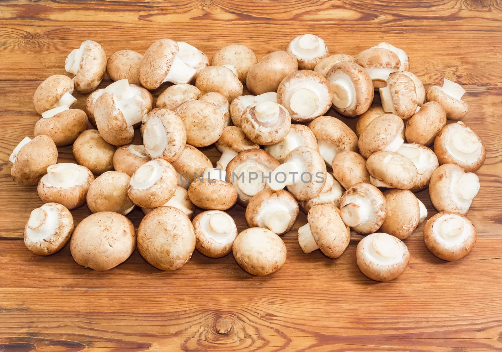 Pile of the fresh whole uncooked edible mushrooms on a surface of the old wooden planks
