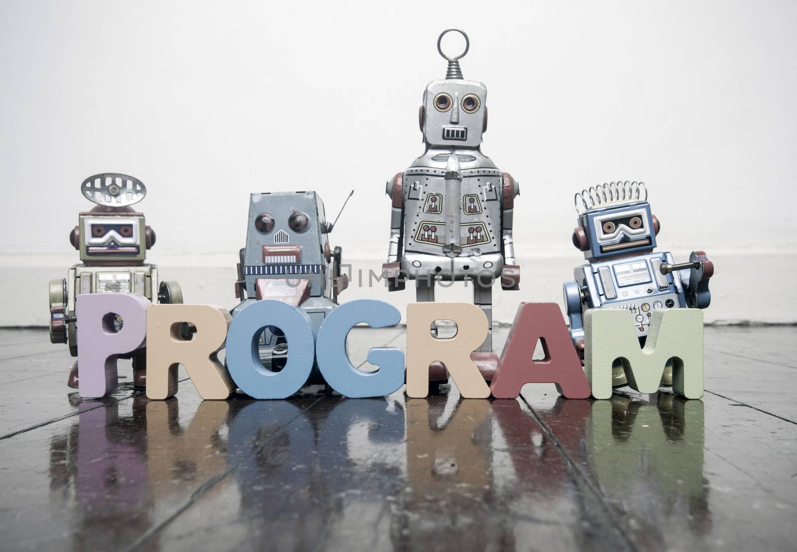 the word PROGRAM with wooden letters and retro toy robots  on an by davincidig